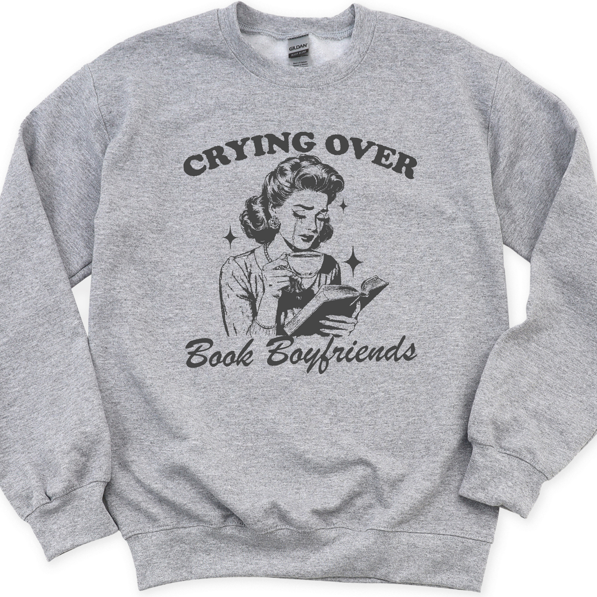 Gray sweatshirt with graphic design and text 'Crying Over Book Boyfriends' on a white background