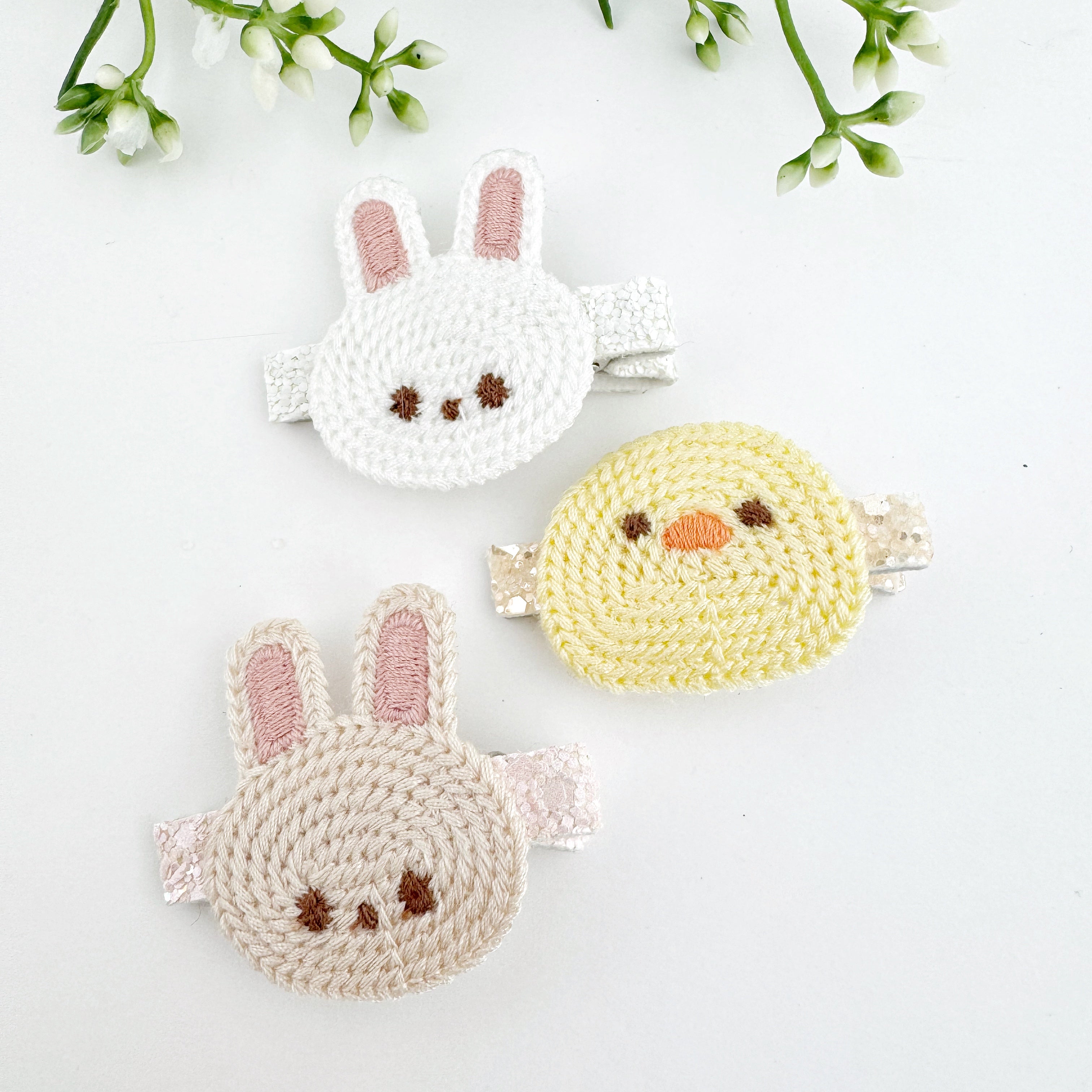 A set of three hair clips with charm designs, including a white rabbit and a yellow chick, displayed against a neutral background.