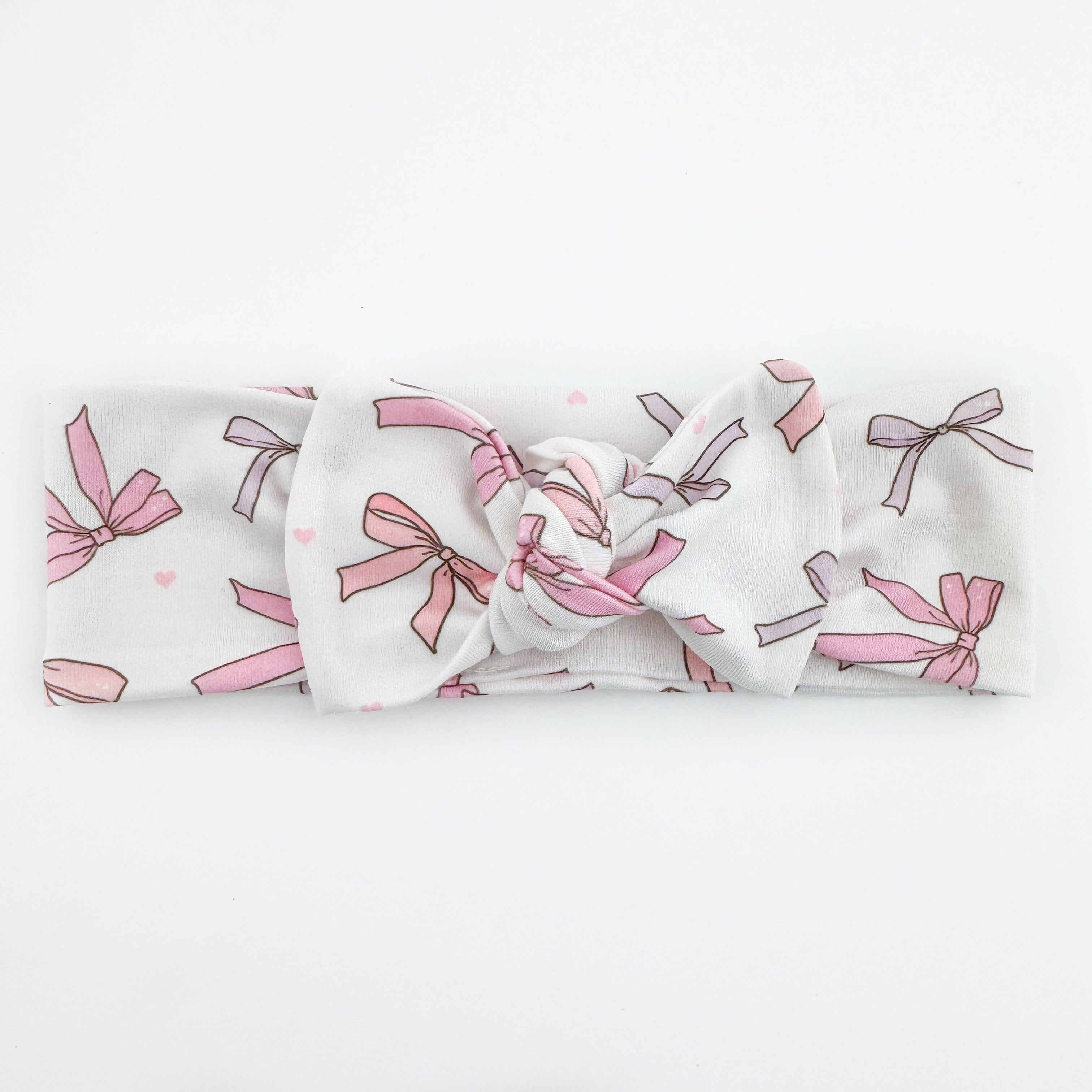 A white knotted baby headband with pink bow pattern