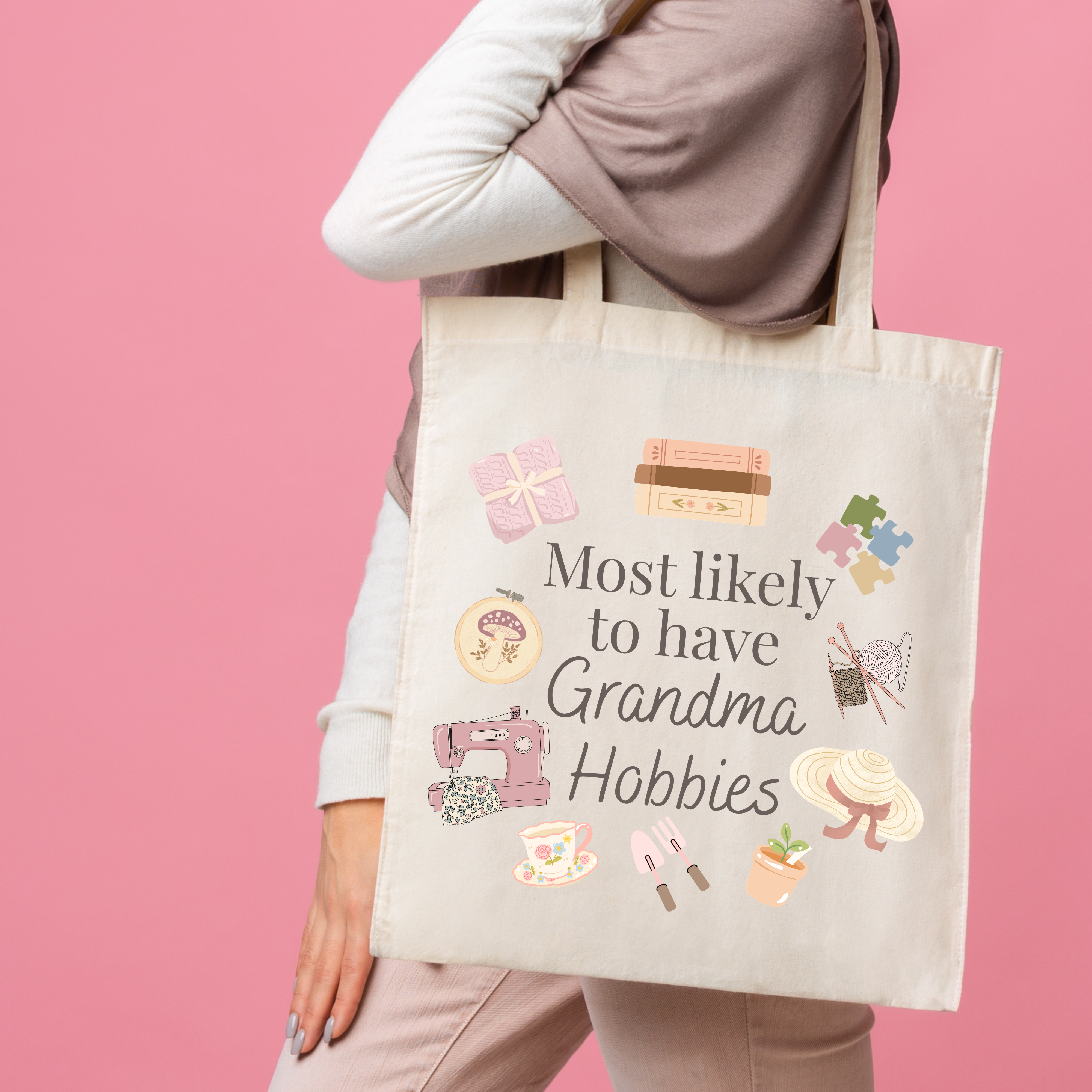 Person holding a tote bag with 'Most likely to have Grandma Hobbies' text and icons on a pink background