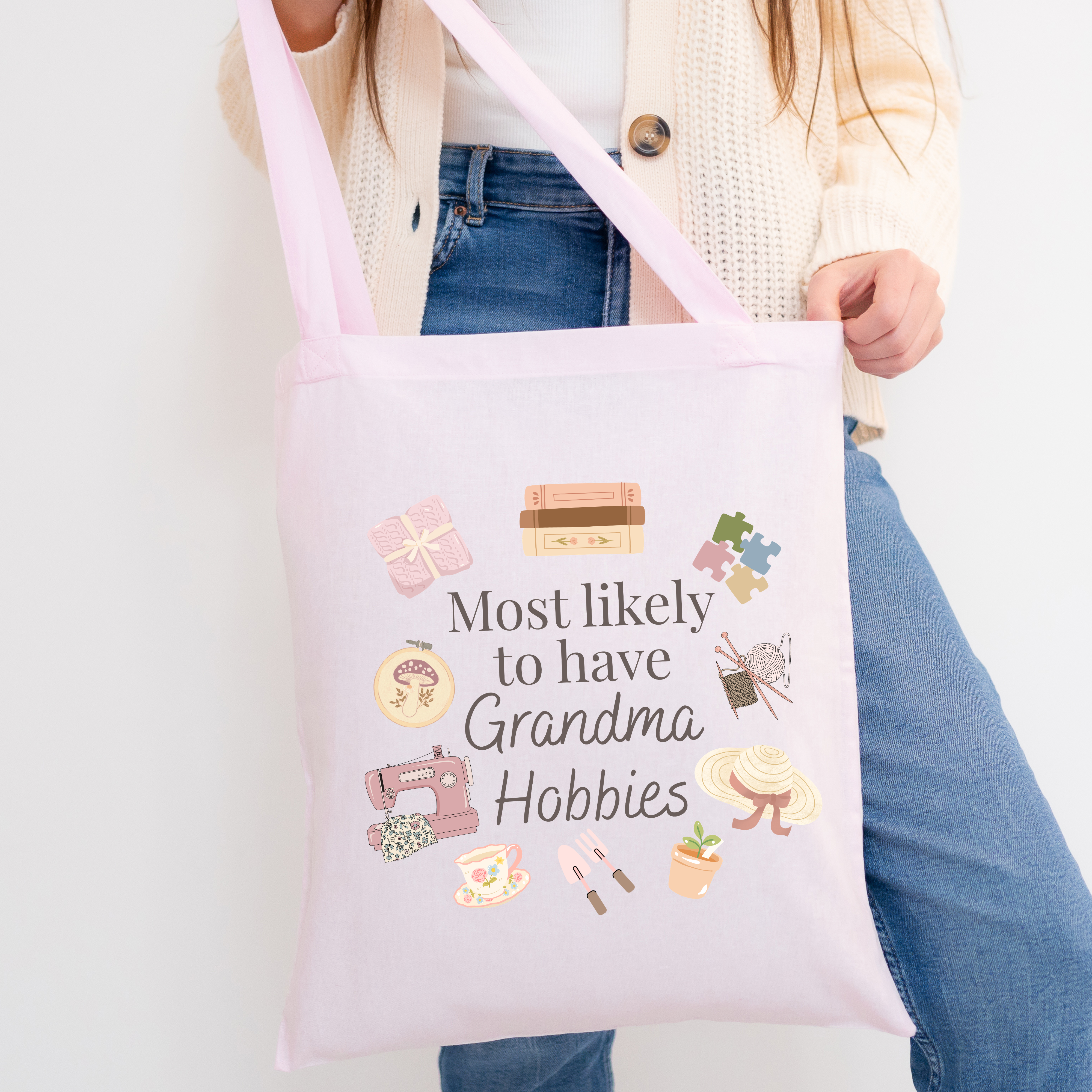 Tote bag with 'Most likely to have Grandma Hobbies' text and icons held by a person.
