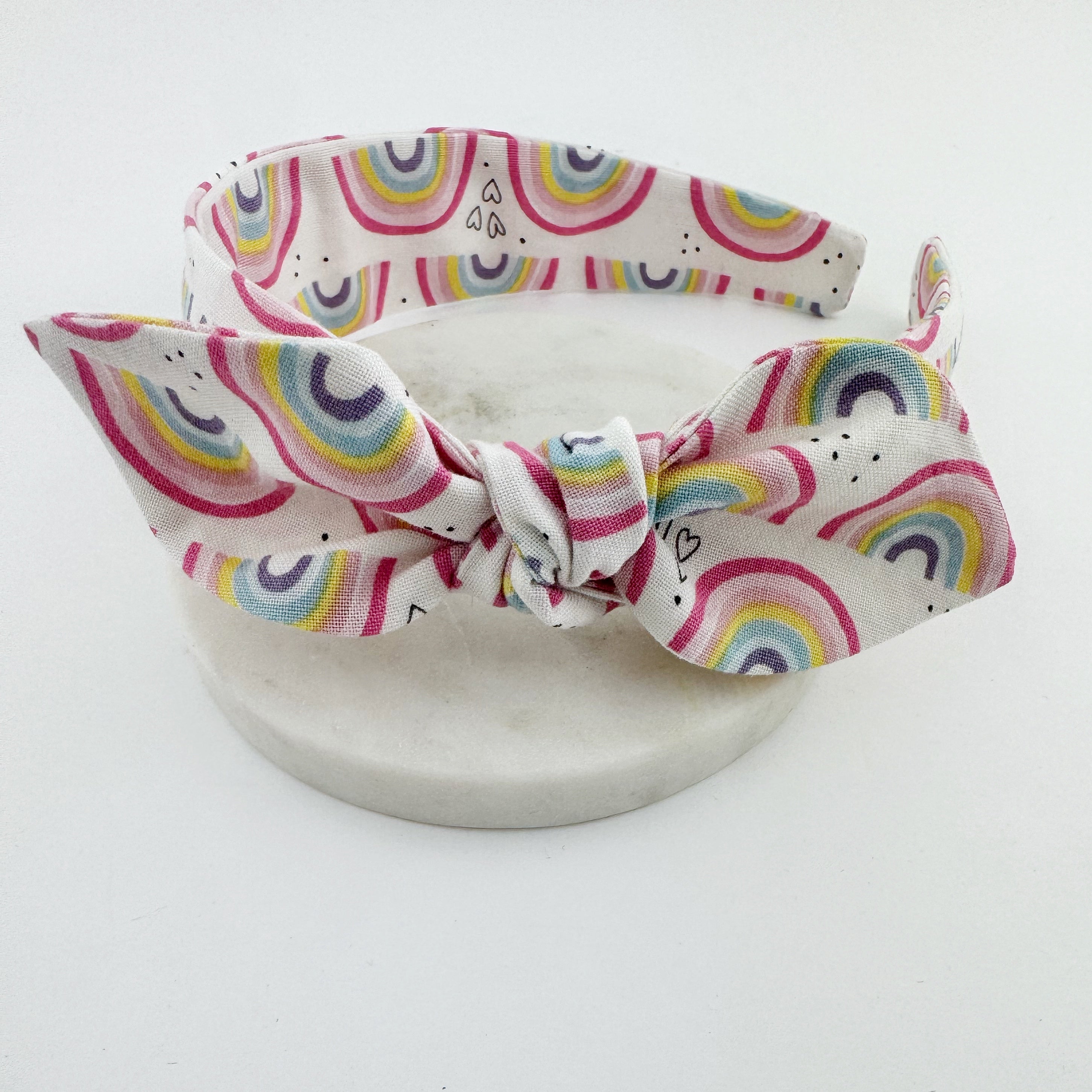 A white knot bow headband with a rainbow patterned fabric