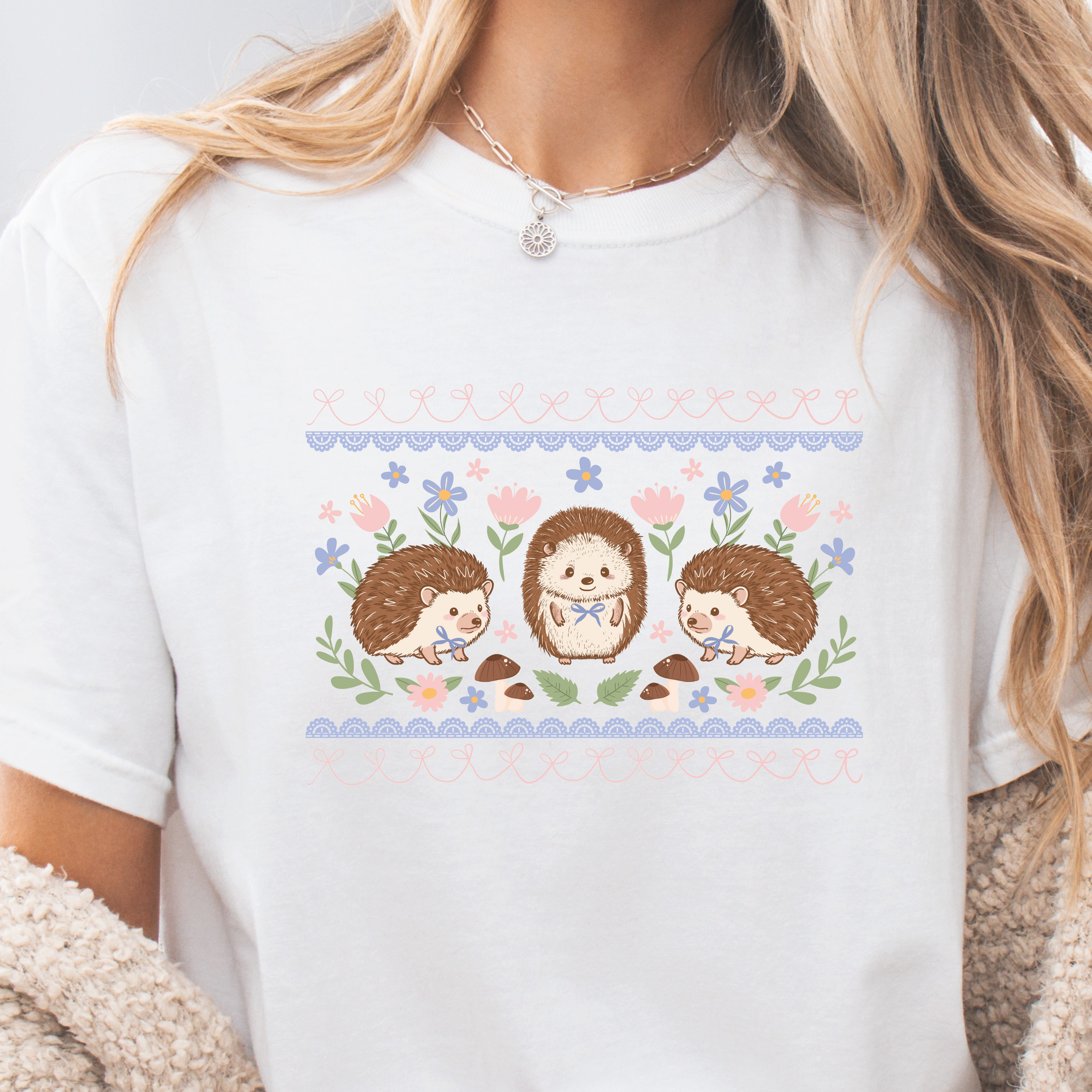 White t-shirt with hedgehog design and floral elements worn by a person.