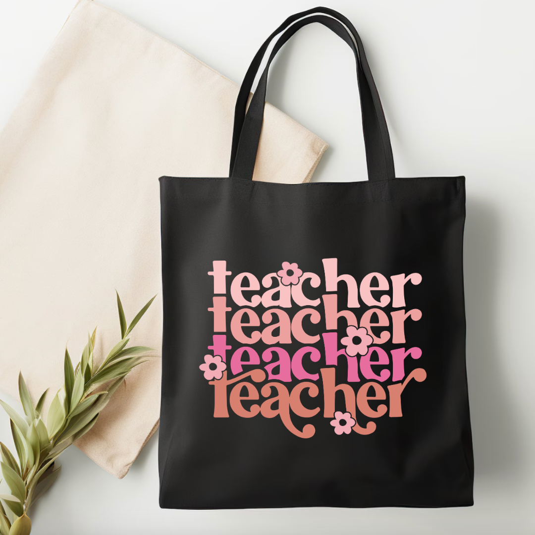 Black tote bag with 'teacher' text in various colors on a light background