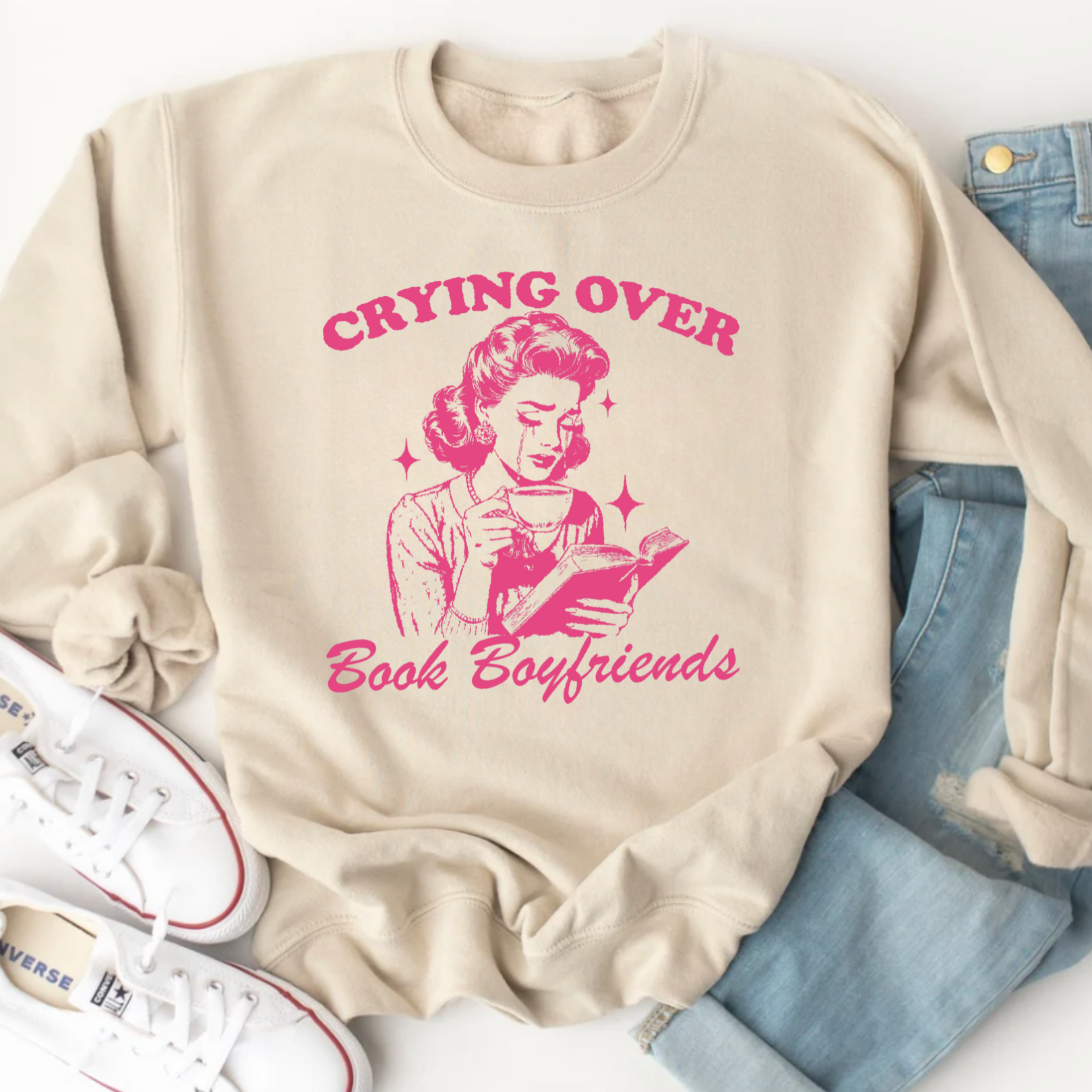 Beige sweatshirt with pink graphic and text 'Crying Over Book Boyfriends' on a white background.