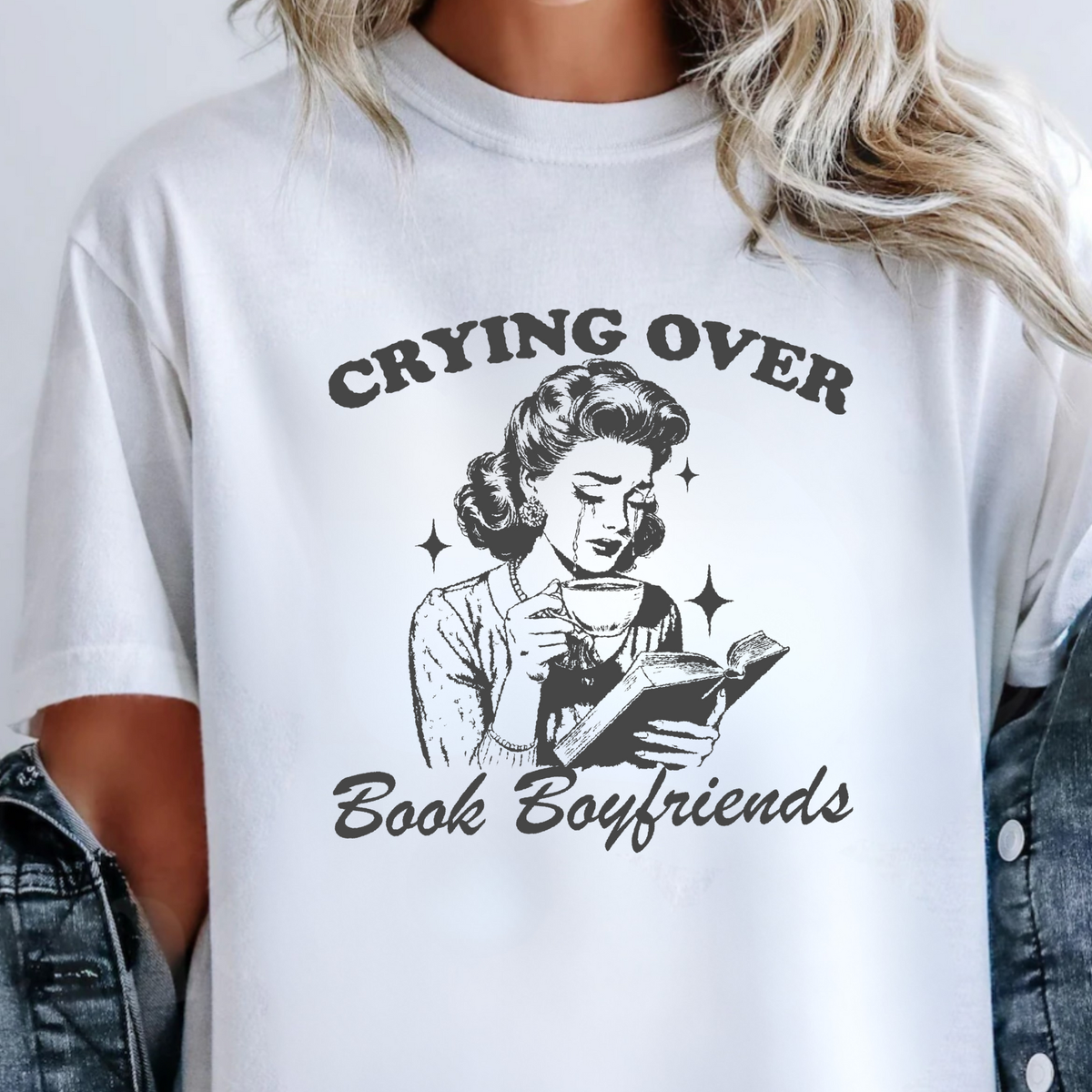White t-shirt with graphic design and text 'Crying Over Book Boyfriends' worn by a person.