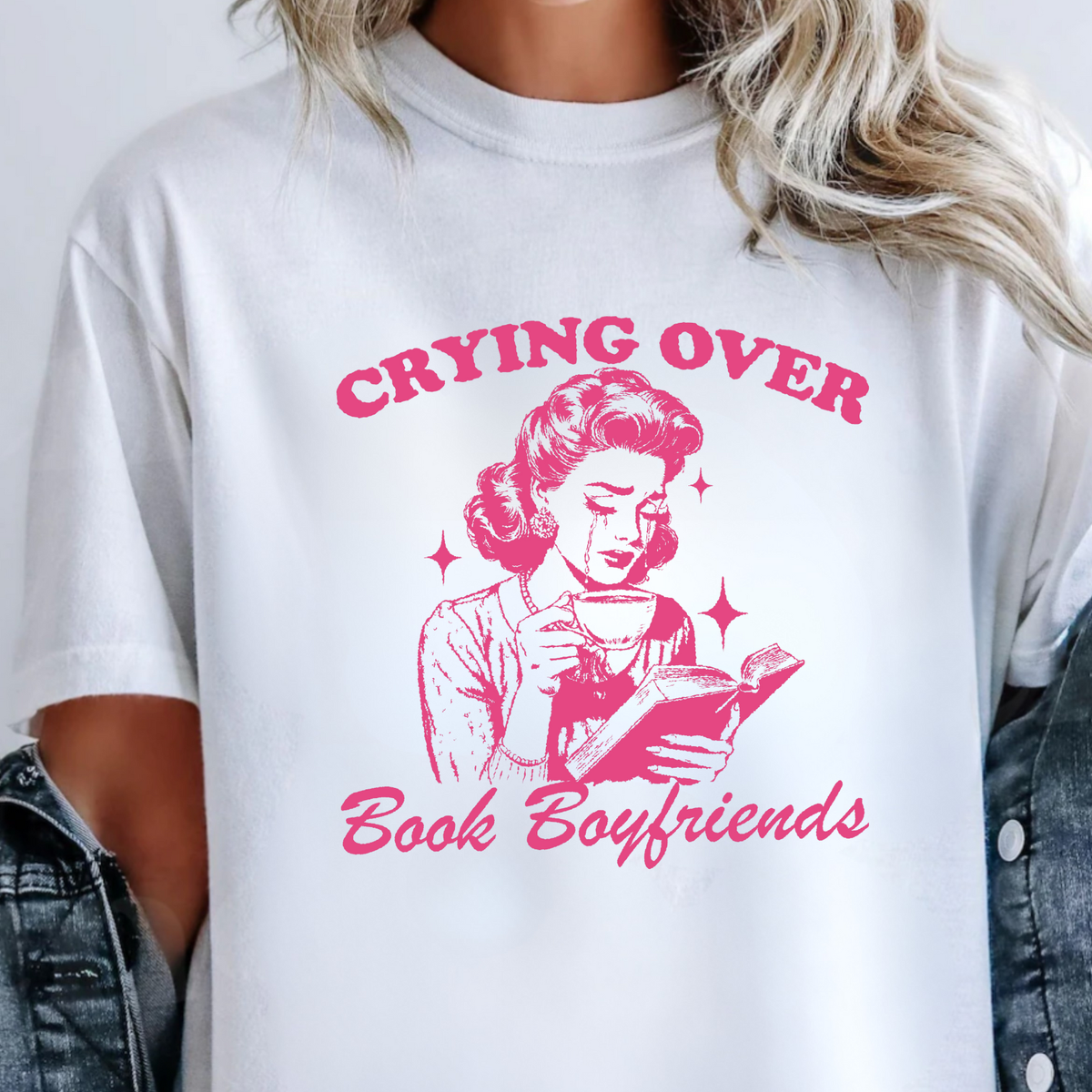 White t-shirt with pink graphic and text 'Crying Over Book Boyfriends' worn by a person.