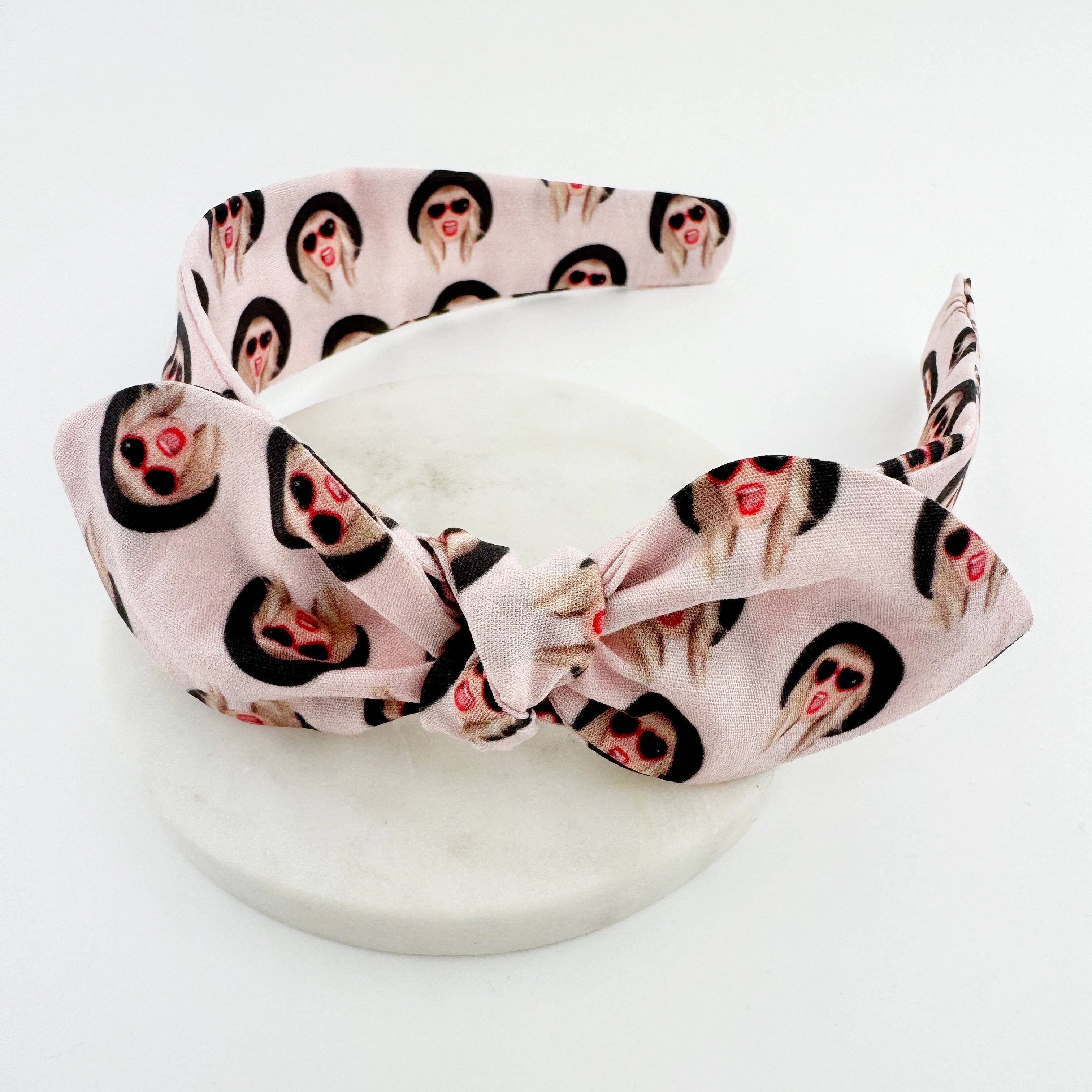 A pink knot bow headband with a Taylor Swift print. 