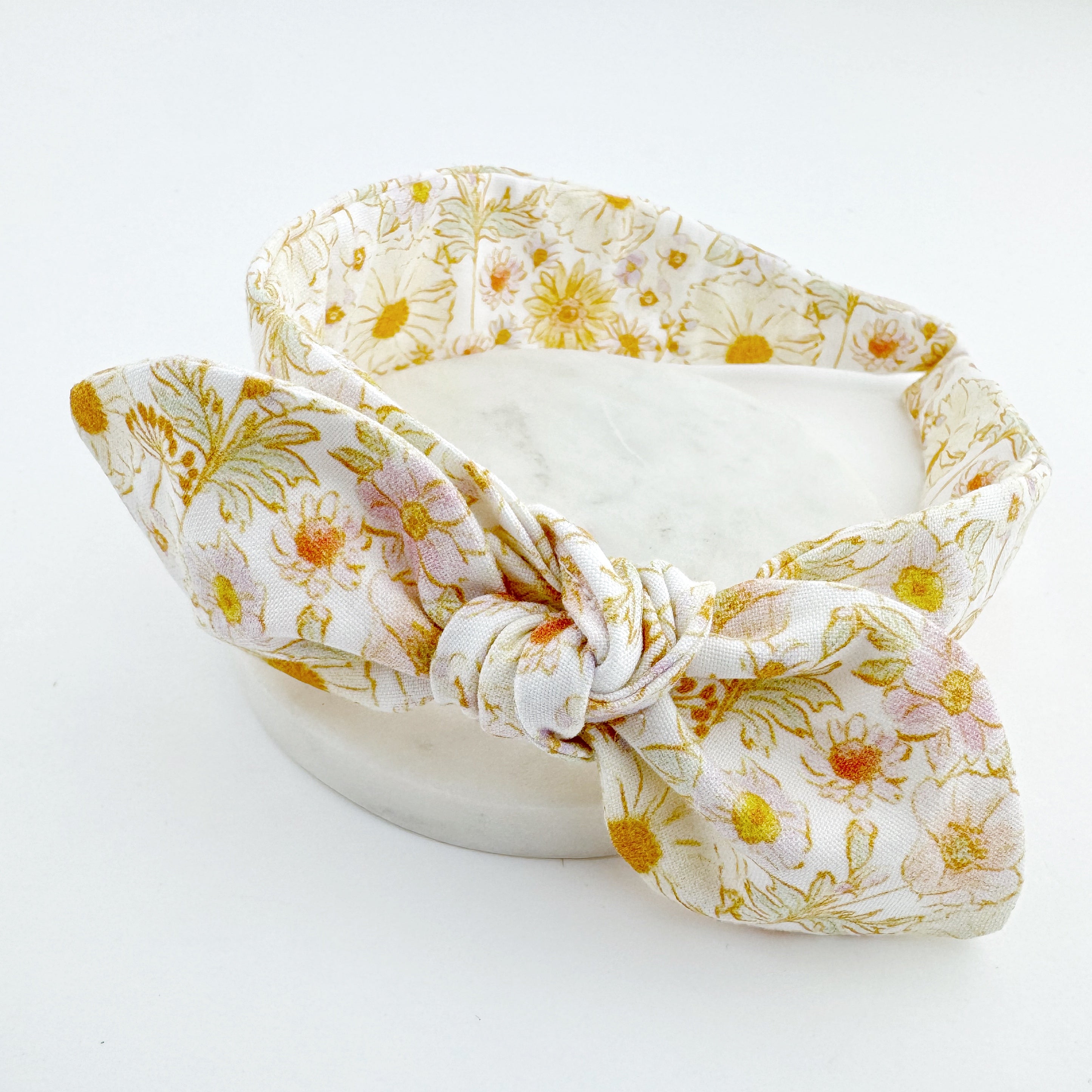 A floral patterned knot bow headband displayed on a white background.