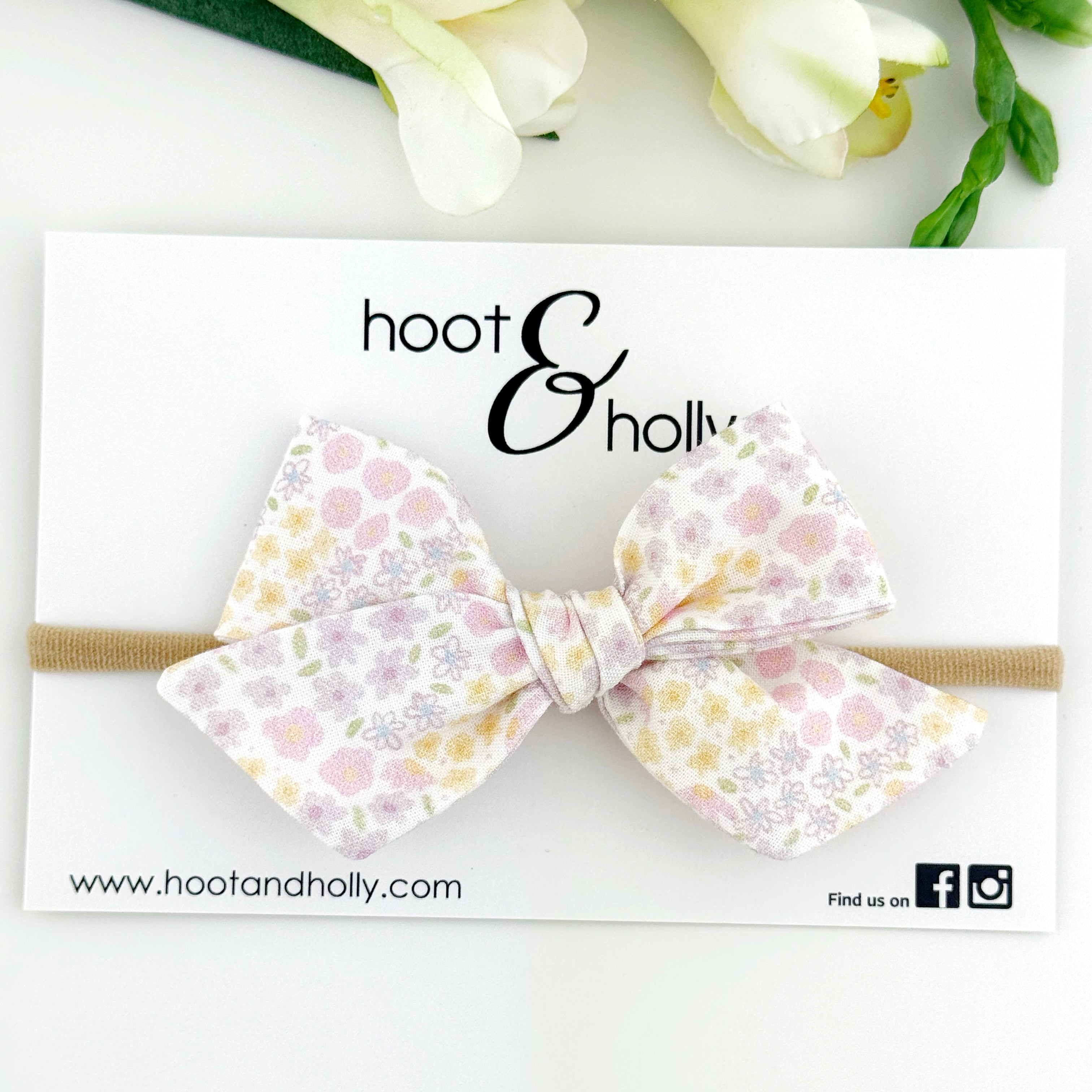 Pastel floral headband with 'hoot & holly' branding on a white background