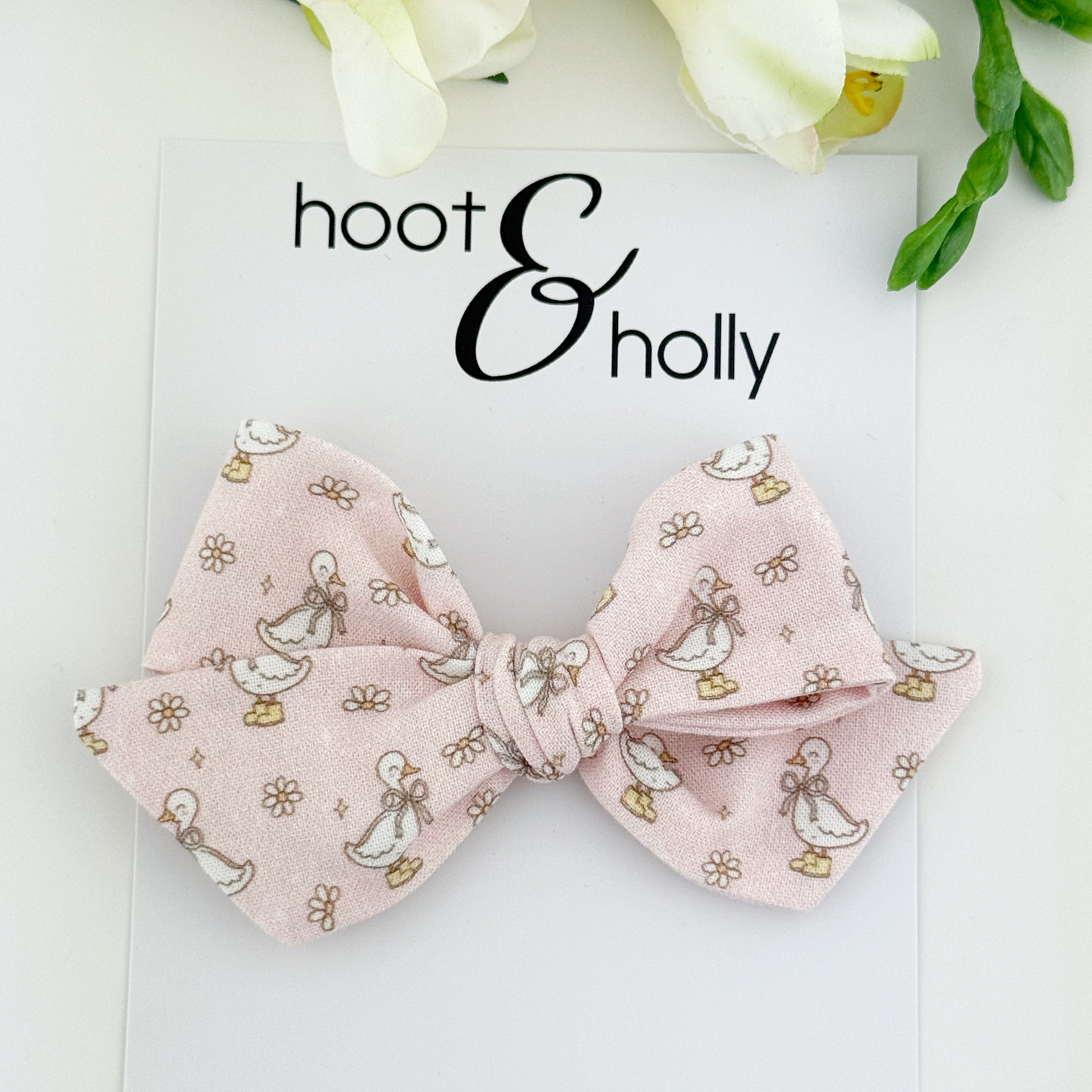 Pink bow with cute goose pattern on a white background with 'hoot & holly' branding.