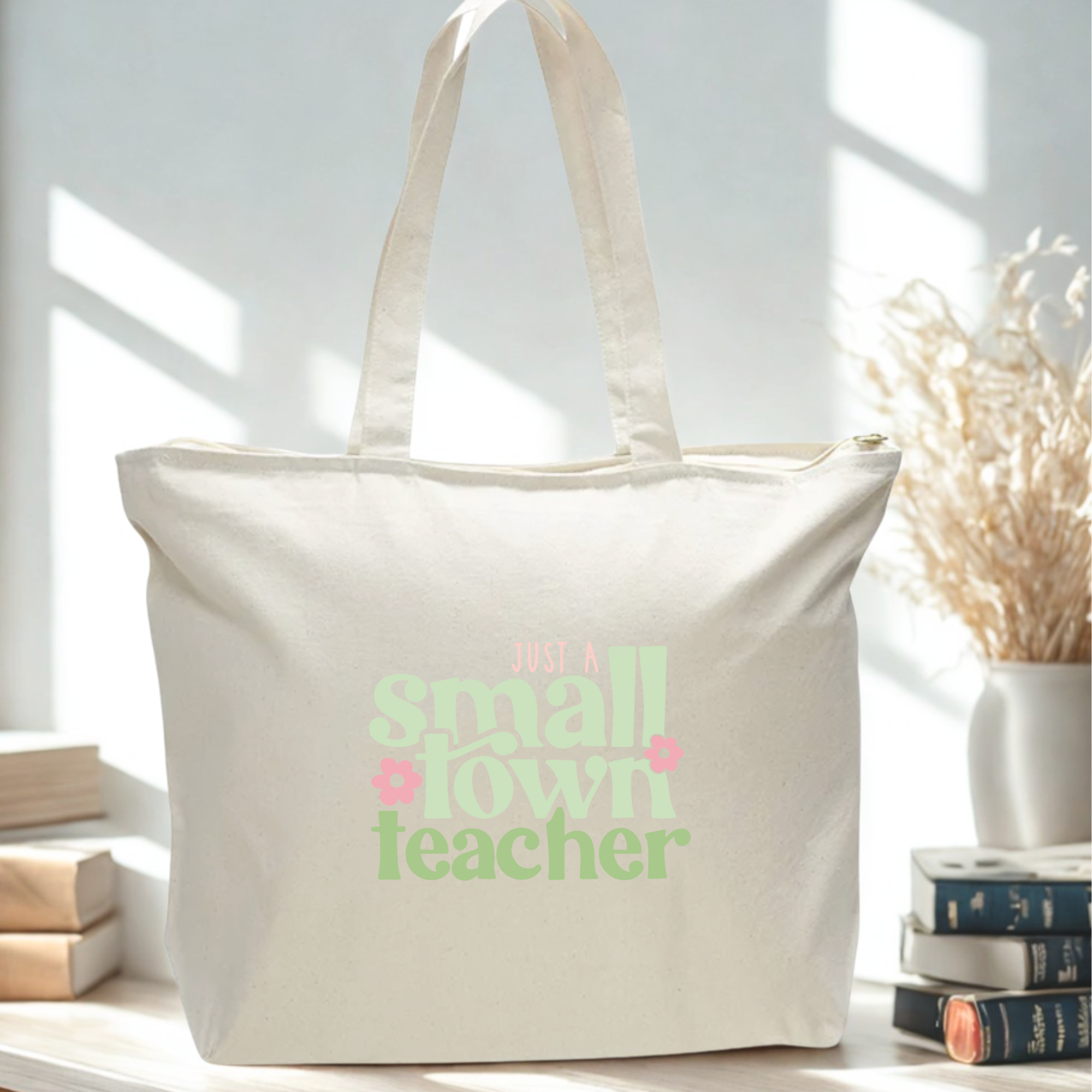 Beige tote bag with 'small town teacher' text on a light background