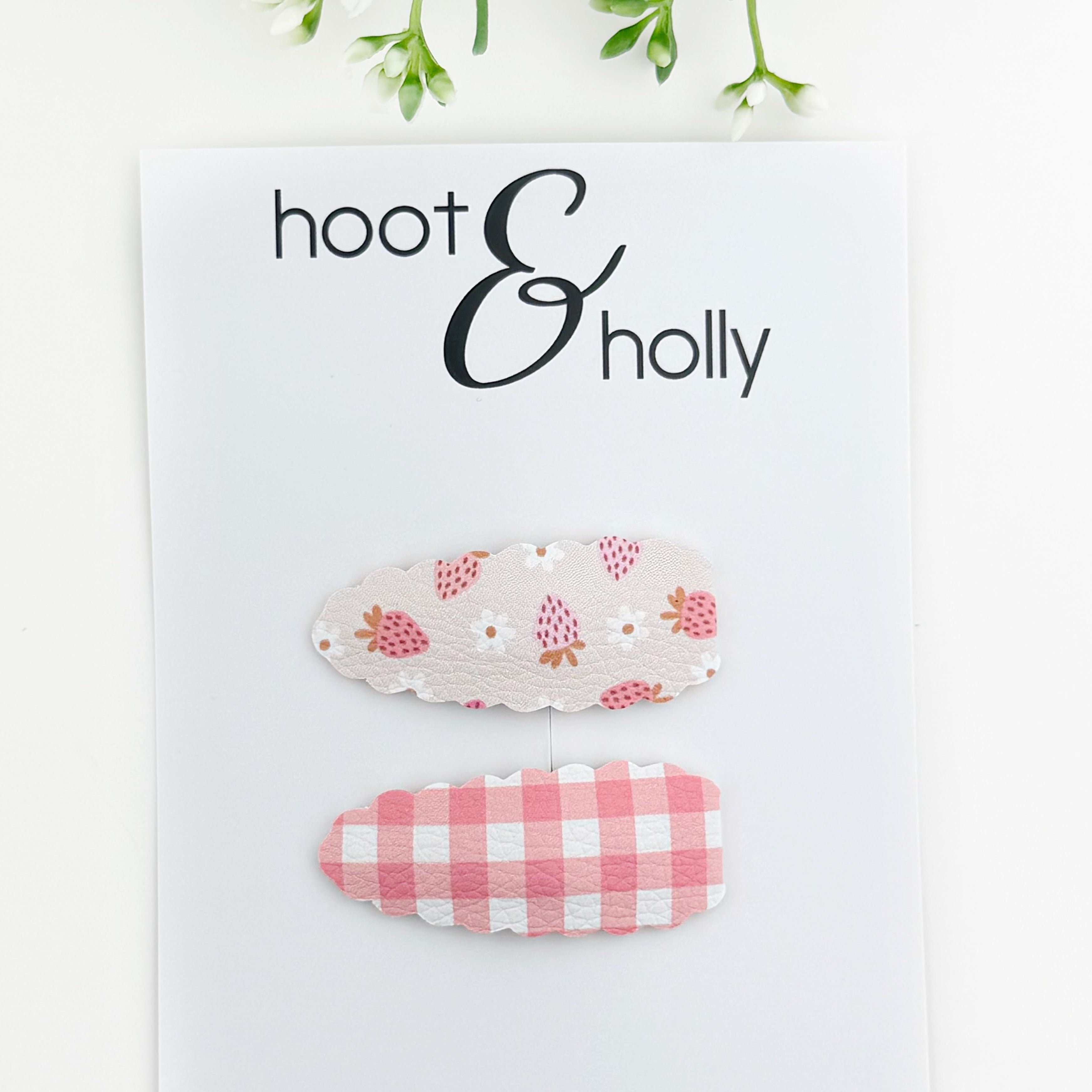 Two floral and checkered hair clips on a 'hoot & holly' branded card.